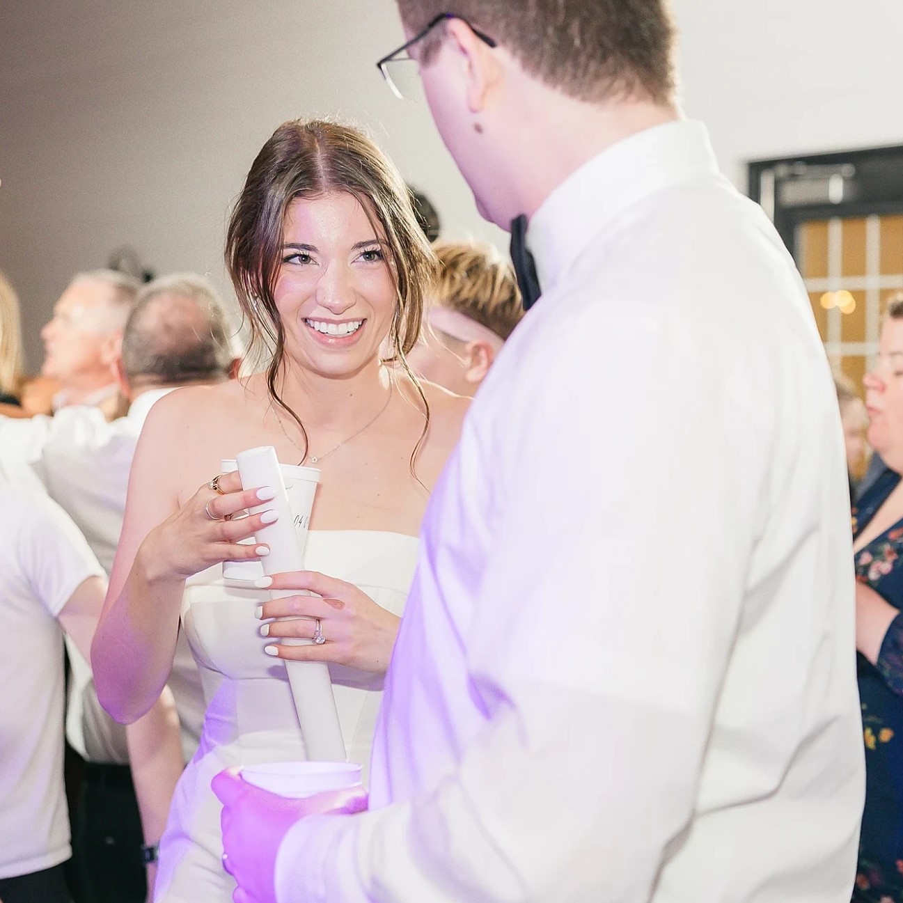 A bride laughing on a packed dance floor