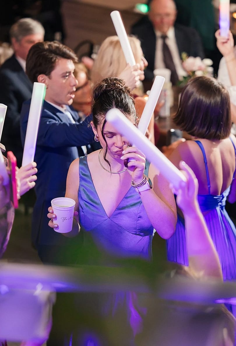 A guest in a blue dress dancing with a foam stick