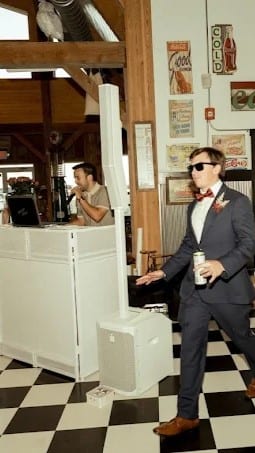 A groom in sunglasses striding past Davin’s white booth