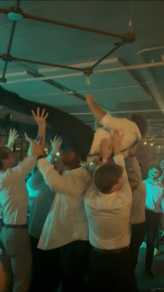 Groomsmen lifting a friend above the crowd