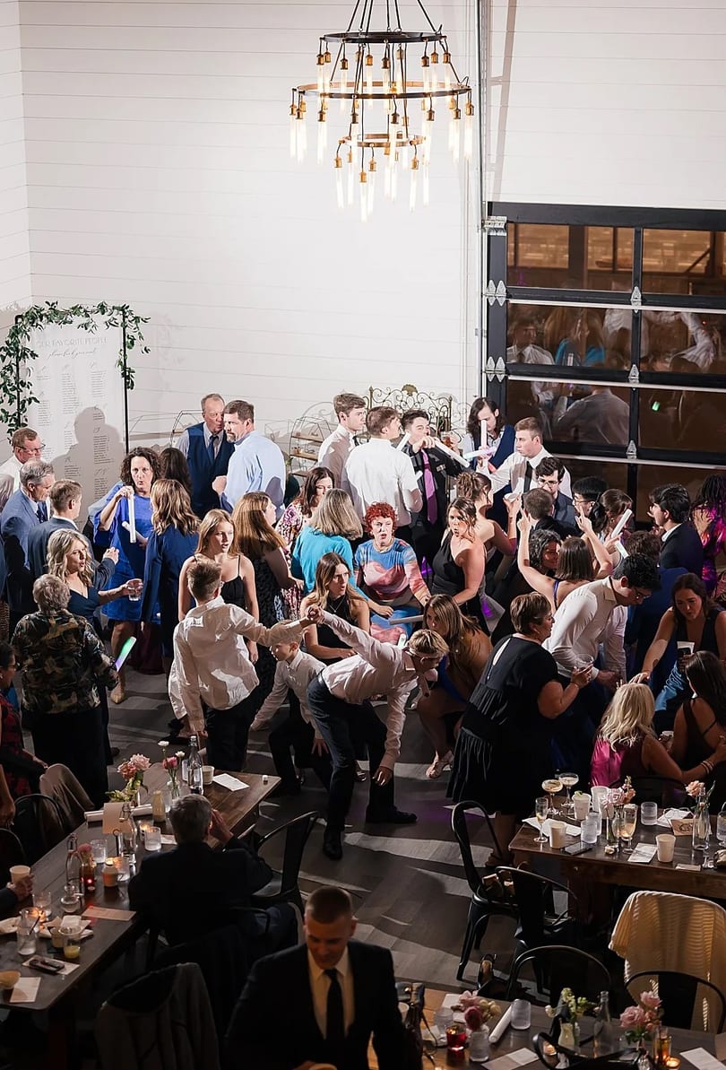 A full dance floor seen from the balcony beneath a chandelier